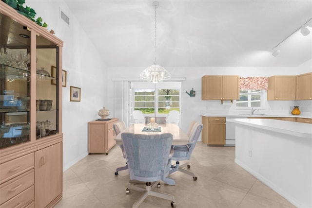 dining area featuring rail lighting, a healthy amount of sunlight, vaulted ceiling, and an inviting chandelier