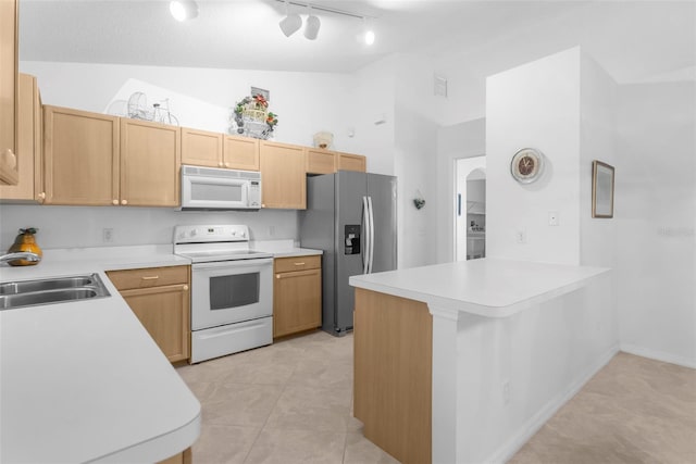 kitchen with kitchen peninsula, lofted ceiling, rail lighting, sink, and white appliances