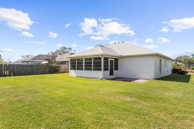 rear view of house featuring a sunroom and a lawn