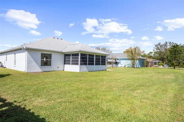 back of house with a sunroom and a lawn