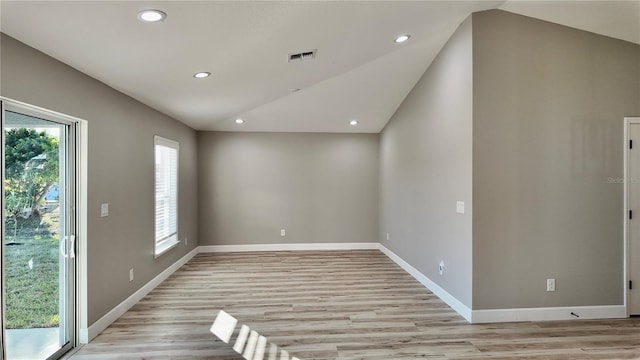 spare room with a wealth of natural light, vaulted ceiling, and light wood-type flooring