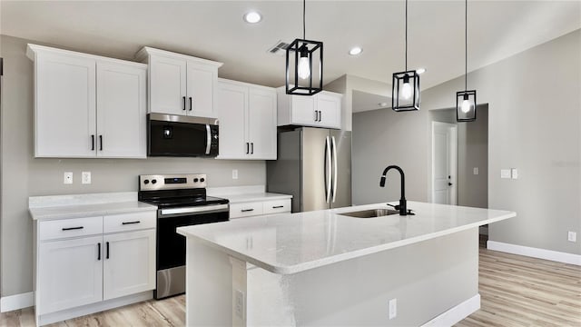 kitchen featuring white cabinets, appliances with stainless steel finishes, pendant lighting, and sink