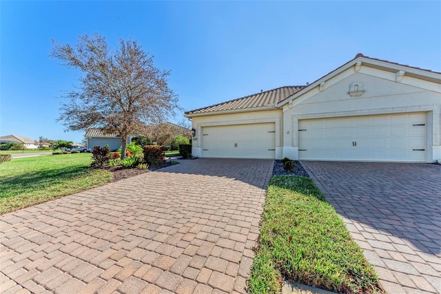 1269 Backspin Dr, Englewood, FL 34223 - view of front of home featuring a tile roof, a front lawn, an attached garage, driveway, and stucco siding