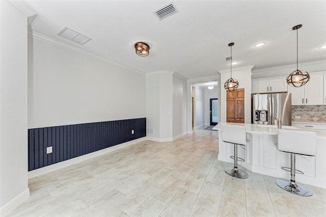 1269 Backspin Dr, Englewood, FL 34223 - kitchen with a breakfast bar area, tasteful backsplash, visible vents, light countertops, and stainless steel refrigerator with ice dispenser