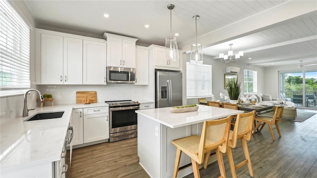 kitchen with stainless steel appliances, a center island, white cabinets, and sink