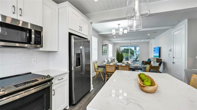 kitchen featuring stainless steel appliances, white cabinets, decorative backsplash, hanging light fixtures, and dark hardwood / wood-style flooring