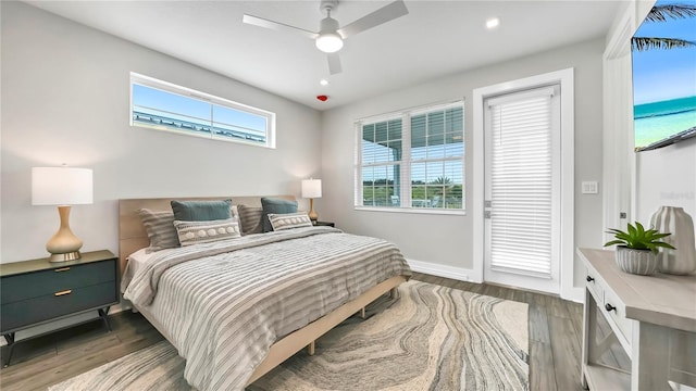 bedroom featuring ceiling fan, dark hardwood / wood-style flooring, and a water view