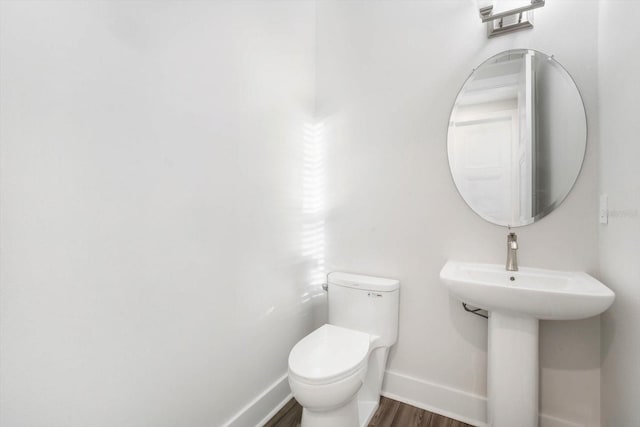 bathroom with toilet, sink, and hardwood / wood-style floors