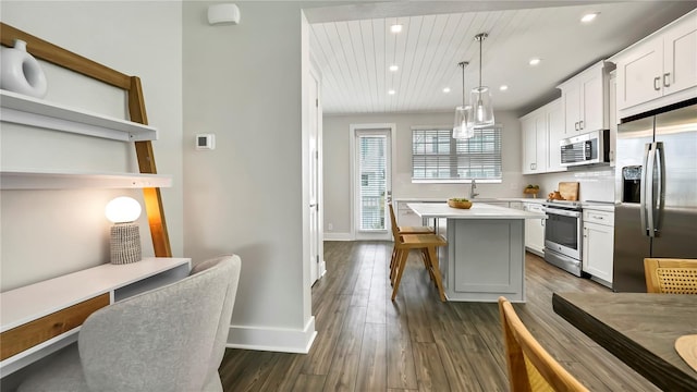 kitchen featuring stainless steel appliances, a center island, white cabinetry, and hanging light fixtures