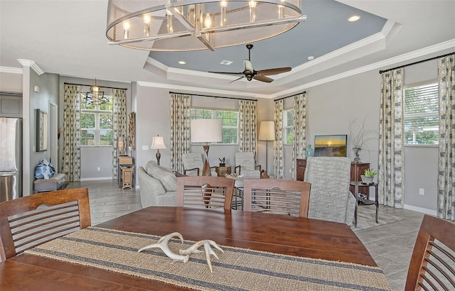 dining room with a raised ceiling, crown molding, and ceiling fan