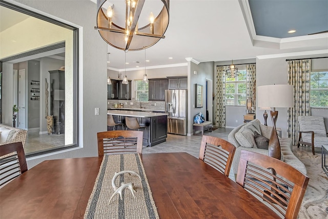 dining space featuring an inviting chandelier, crown molding, light hardwood / wood-style floors, and sink