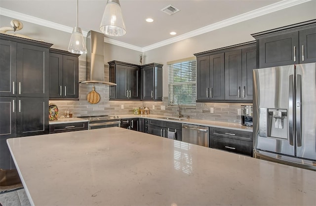 kitchen featuring decorative light fixtures, range hood, sink, ornamental molding, and stainless steel appliances