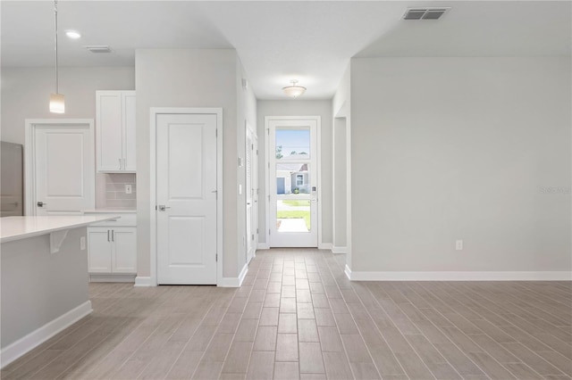 foyer featuring light wood-type flooring, baseboards, and visible vents