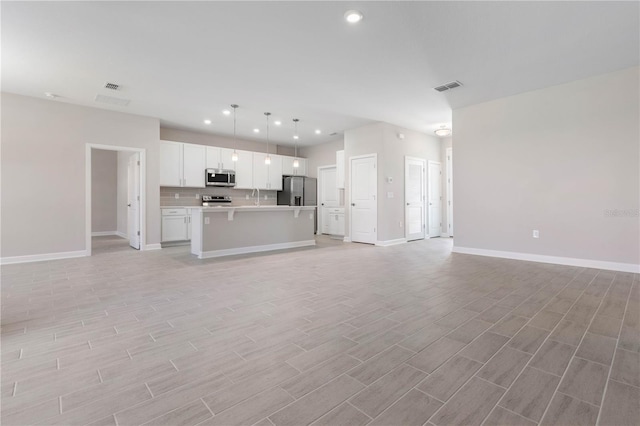 unfurnished living room featuring visible vents, baseboards, light wood-style flooring, and recessed lighting