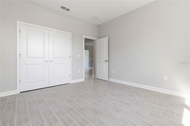unfurnished bedroom featuring baseboards, light wood-style floors, a closet, and visible vents