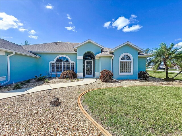 ranch-style home with stucco siding and a front yard
