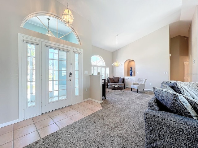 carpeted foyer featuring high vaulted ceiling, baseboards, tile patterned floors, and a notable chandelier
