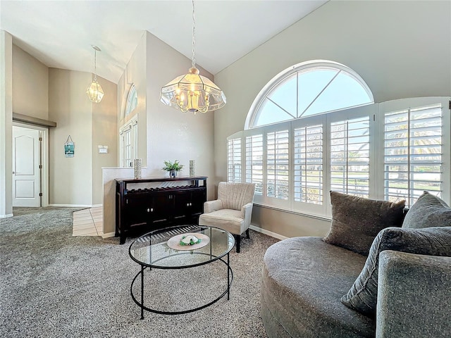 living area featuring carpet floors, high vaulted ceiling, a notable chandelier, and baseboards