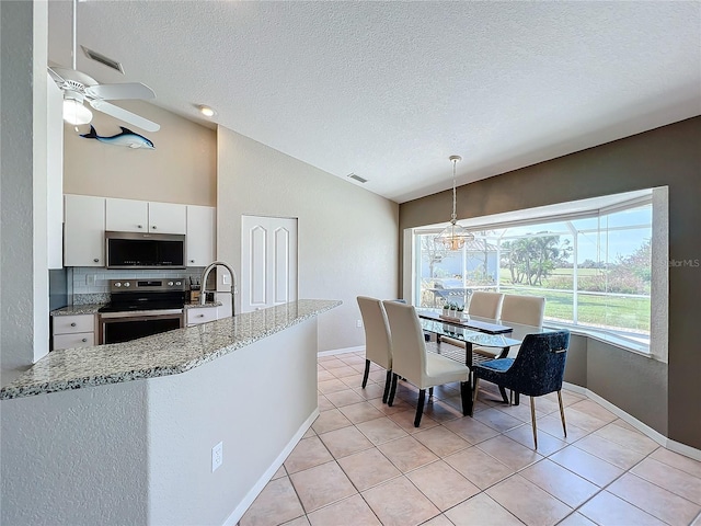 kitchen featuring vaulted ceiling, pendant lighting, white cabinetry, appliances with stainless steel finishes, and ceiling fan