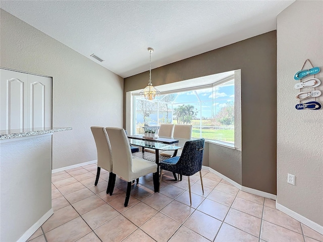dining space with baseboards, a textured wall, light tile patterned flooring, and visible vents