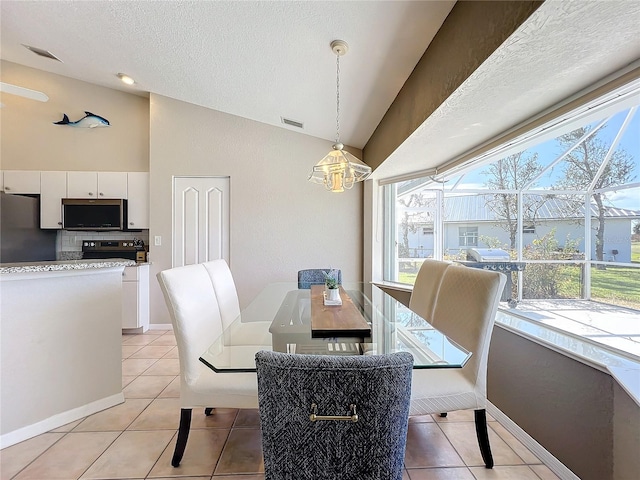 dining space featuring a textured ceiling, light tile patterned floors, and vaulted ceiling