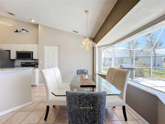 dining space featuring light tile patterned flooring, a textured ceiling, a chandelier, vaulted ceiling, and visible vents