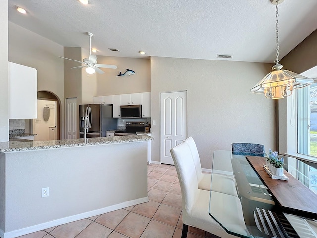 kitchen with appliances with stainless steel finishes, kitchen peninsula, white cabinetry, high vaulted ceiling, and light tile patterned floors