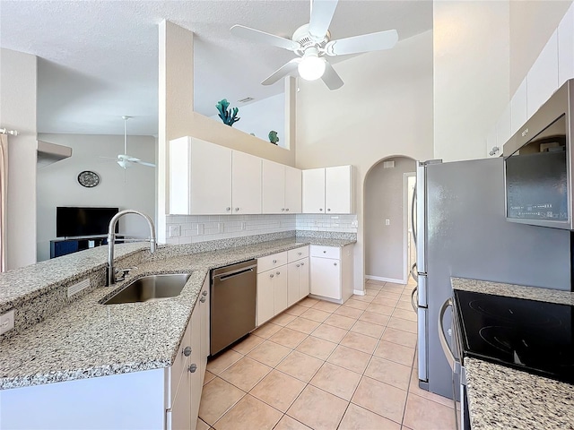 kitchen featuring sink, white cabinets, light tile patterned floors, appliances with stainless steel finishes, and high vaulted ceiling