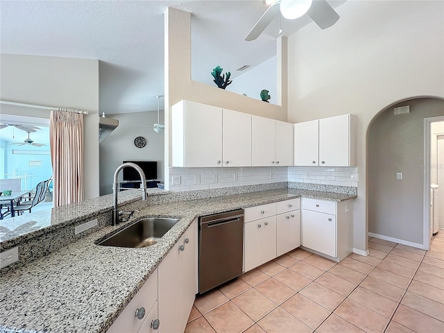 kitchen featuring sink, stainless steel dishwasher, white cabinetry, light stone counters, and high vaulted ceiling