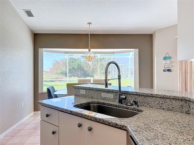 kitchen featuring white cabinetry, light stone counters, a textured ceiling, and sink