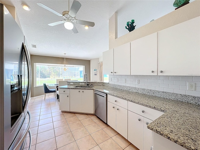 kitchen featuring kitchen peninsula, stainless steel appliances, sink, white cabinetry, and a textured ceiling