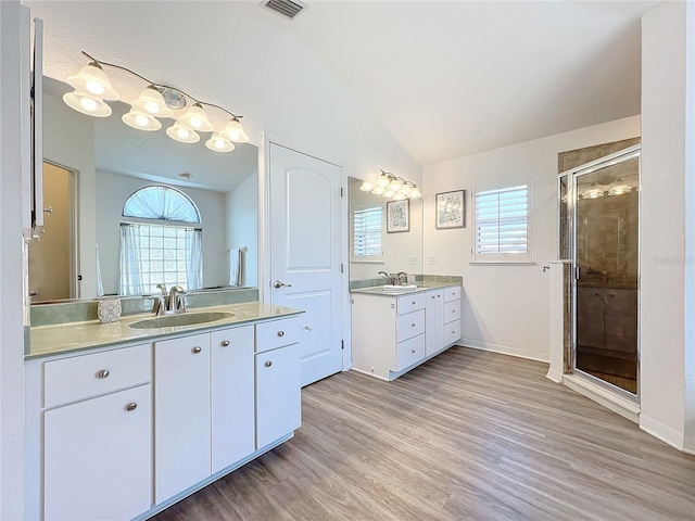 bathroom with vanity, wood-type flooring, vaulted ceiling, and a shower with door