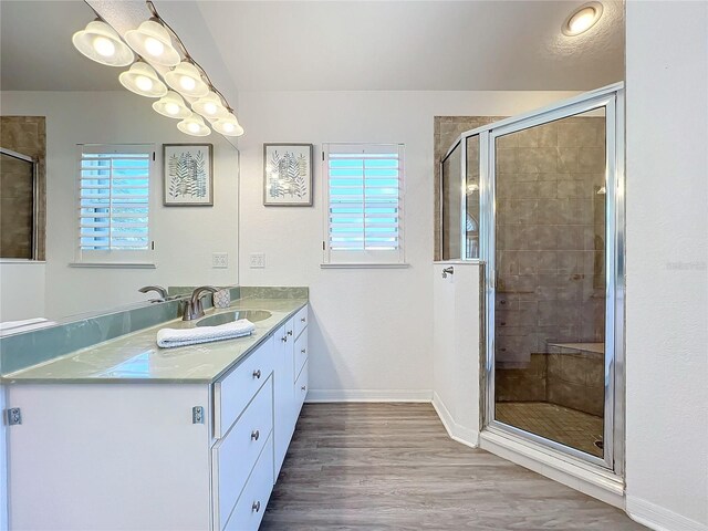 full bath featuring baseboards, vanity, a stall shower, and wood finished floors