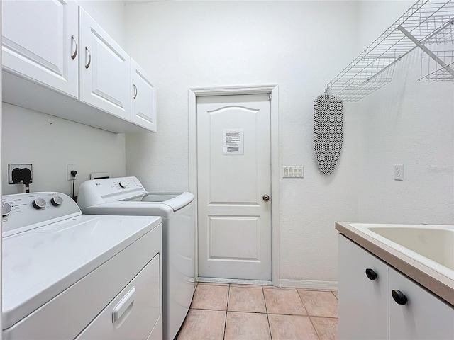 laundry area featuring washing machine and dryer, light tile patterned floors, and cabinets