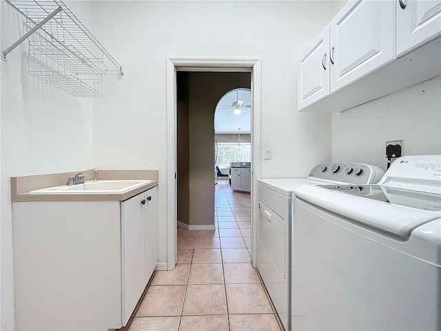 clothes washing area featuring sink, light tile patterned floors, washing machine and clothes dryer, cabinets, and ceiling fan