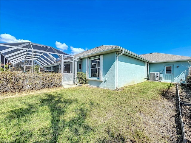 view of home's exterior featuring a yard, cooling unit, glass enclosure, and stucco siding