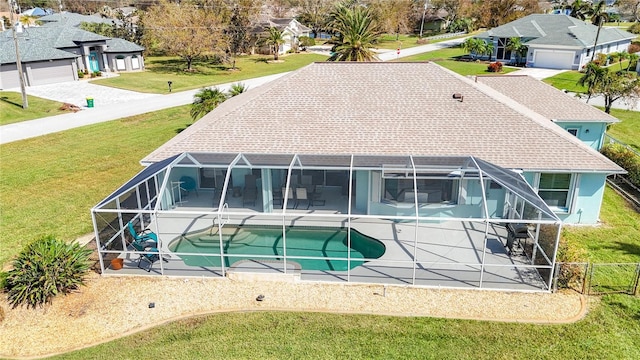 back of property with an outdoor pool, a patio area, glass enclosure, fence, and a yard