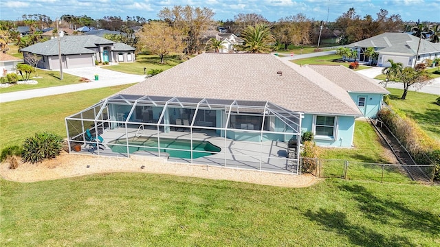 rear view of property featuring a garage, a yard, a patio, and a lanai