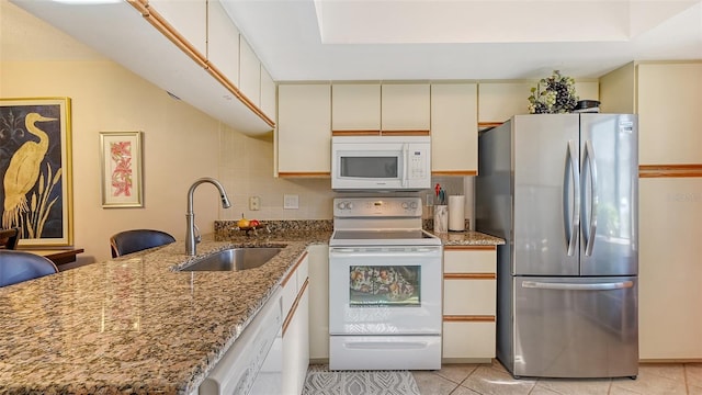 kitchen with tasteful backsplash, light tile patterned floors, light stone countertops, sink, and white appliances