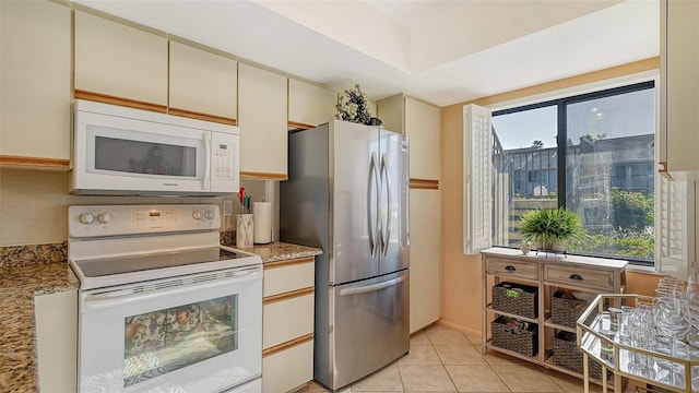 kitchen featuring tasteful backsplash, a wealth of natural light, light tile patterned floors, and white appliances