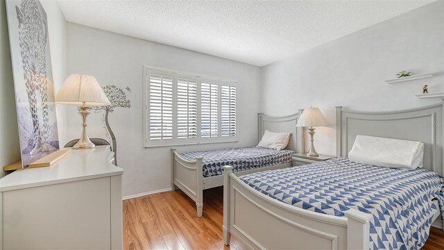 bedroom with a textured ceiling and light wood-type flooring