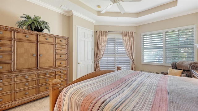 bedroom with ceiling fan, light carpet, ornamental molding, and a raised ceiling