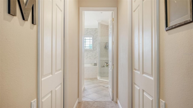 corridor with crown molding and light tile patterned flooring