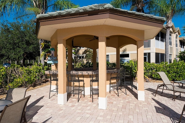 view of patio featuring exterior bar and ceiling fan