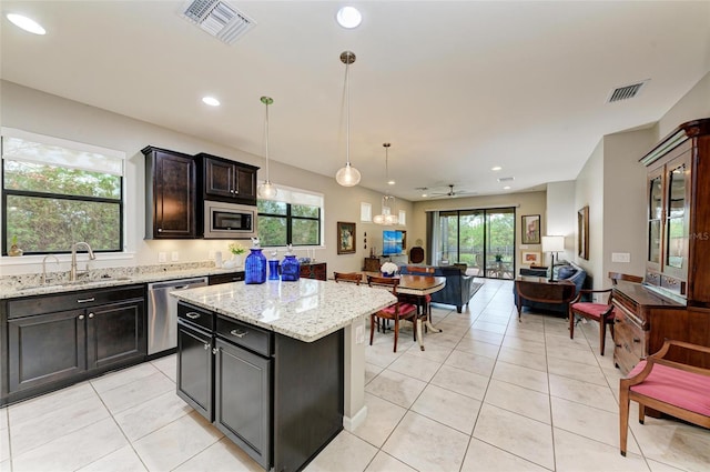 kitchen with a wealth of natural light, appliances with stainless steel finishes, ceiling fan, and a center island