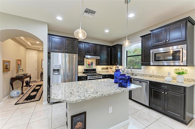 kitchen featuring a kitchen island, pendant lighting, appliances with stainless steel finishes, and light stone counters