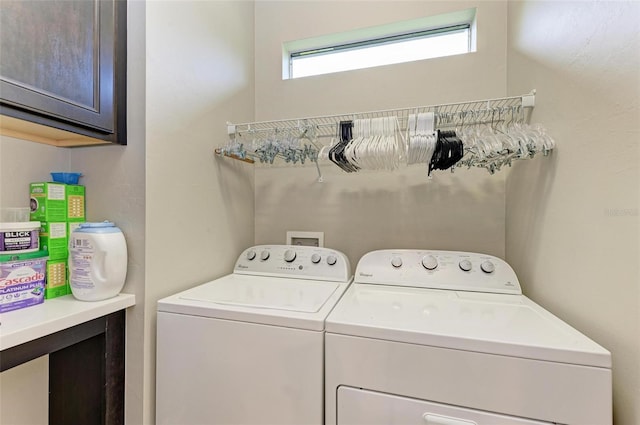 clothes washing area with cabinets and washing machine and dryer