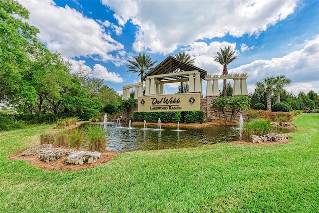 community sign featuring a yard and a water view