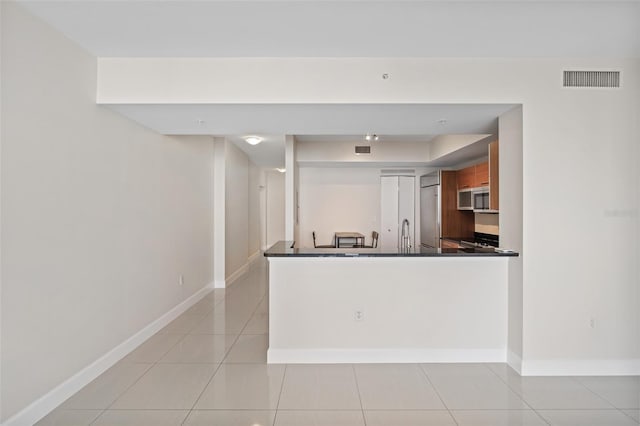 kitchen featuring sink, light tile patterned flooring, and kitchen peninsula