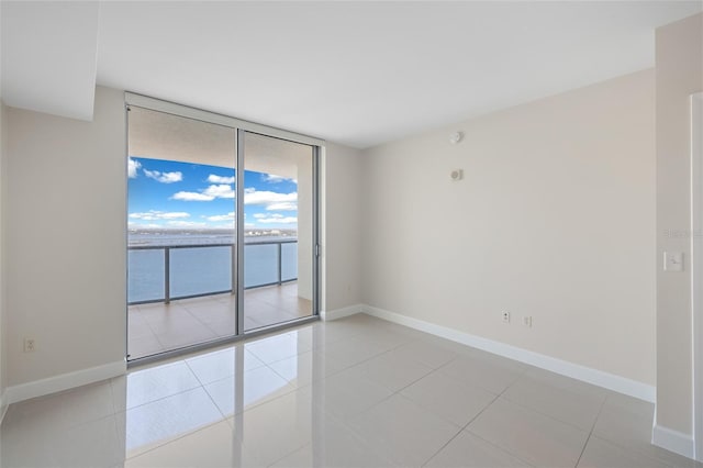 empty room featuring expansive windows, a water view, and light tile patterned floors